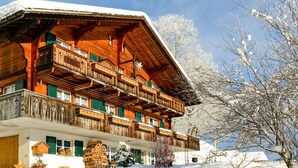 Una cabaña de madera con balcón, rodeada de nieve y árboles.
