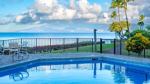 A pool with a view of the ocean and palm trees. - Napili Point | Oceanfront 2 BR, Sleeps 8 | Car Incl. w/ 6+ Nights | NAP ML-3494 by KBM (Lahaina)