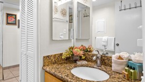 A bathroom with a granite countertop, a white sink, a mirror, and a towel rack. - Napili Point | Oceanfront 2 BR, Sleeps 8 | Car Incl. w/ 6+ Nights | NAP ML-3494 by KBM (Lahaina)