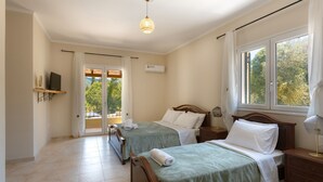 Quarto de hotel com duas camas, uma luminária no teto, uma televisão em uma estante e uma janela com cortinas.