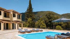 Uma área de piscina com espreguiçadeiras e um edifício com telhado em azulejos.
