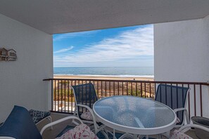 A balcony with a glass table and chairs, overlooking a beach. - Pyramid-2 Bedroom With Private Balcony and Ocean Views (Ocean City)