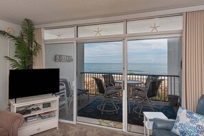 A balcony with a TV, seating, and a view of the ocean. - Pyramid-2 Bedroom With Private Balcony and Ocean Views (Ocean City)