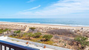 A beach view with a fenced area, a clear sky, and a distant shoreline.