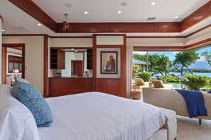 Quarto com cama grande, área de estar com vista e banheiro com espelho e armários.