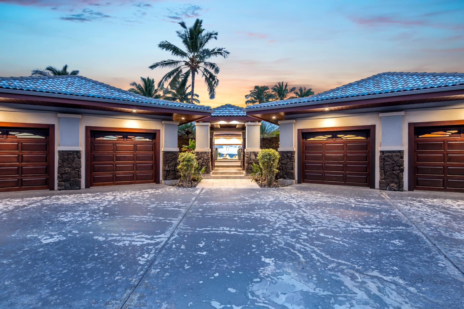 A building with multiple garage doors, a stone facade, and a paved driveway.