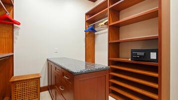 A walk-in closet with wooden shelving, a granite countertop, and a small trash bin.