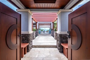 A covered walkway leading to a pool area with stone walls and wooden doors.