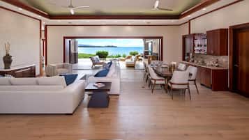 A spacious living area with a view of the sea, a dining area, and a kitchen with wooden cabinets.