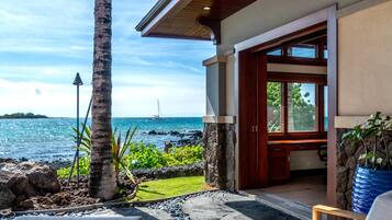 A modern house with a stone exterior, a wooden deck, and a view of the ocean.