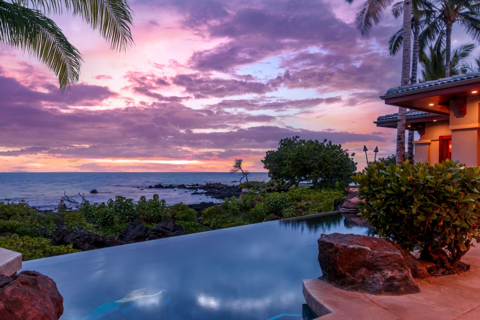 A pool with a view of the ocean and a sunset.