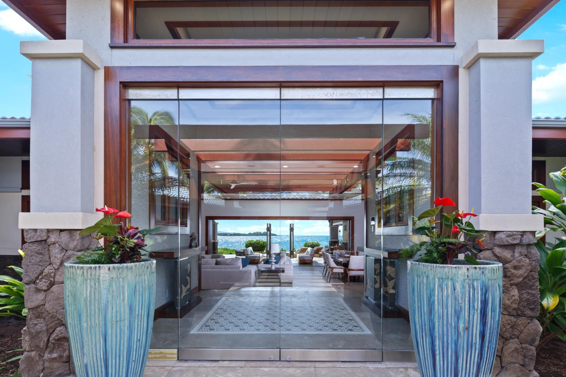 A modern building with a covered entrance, large windows, and a view of the sea.