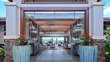 A modern building with a covered entrance, large windows, and a view of the sea.