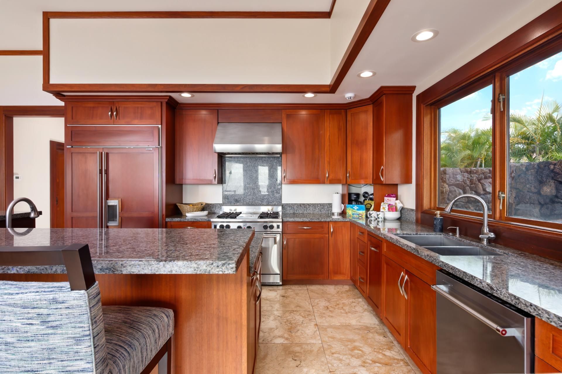 A modern kitchen with granite countertops, stainless steel appliances, and wooden cabinetry.