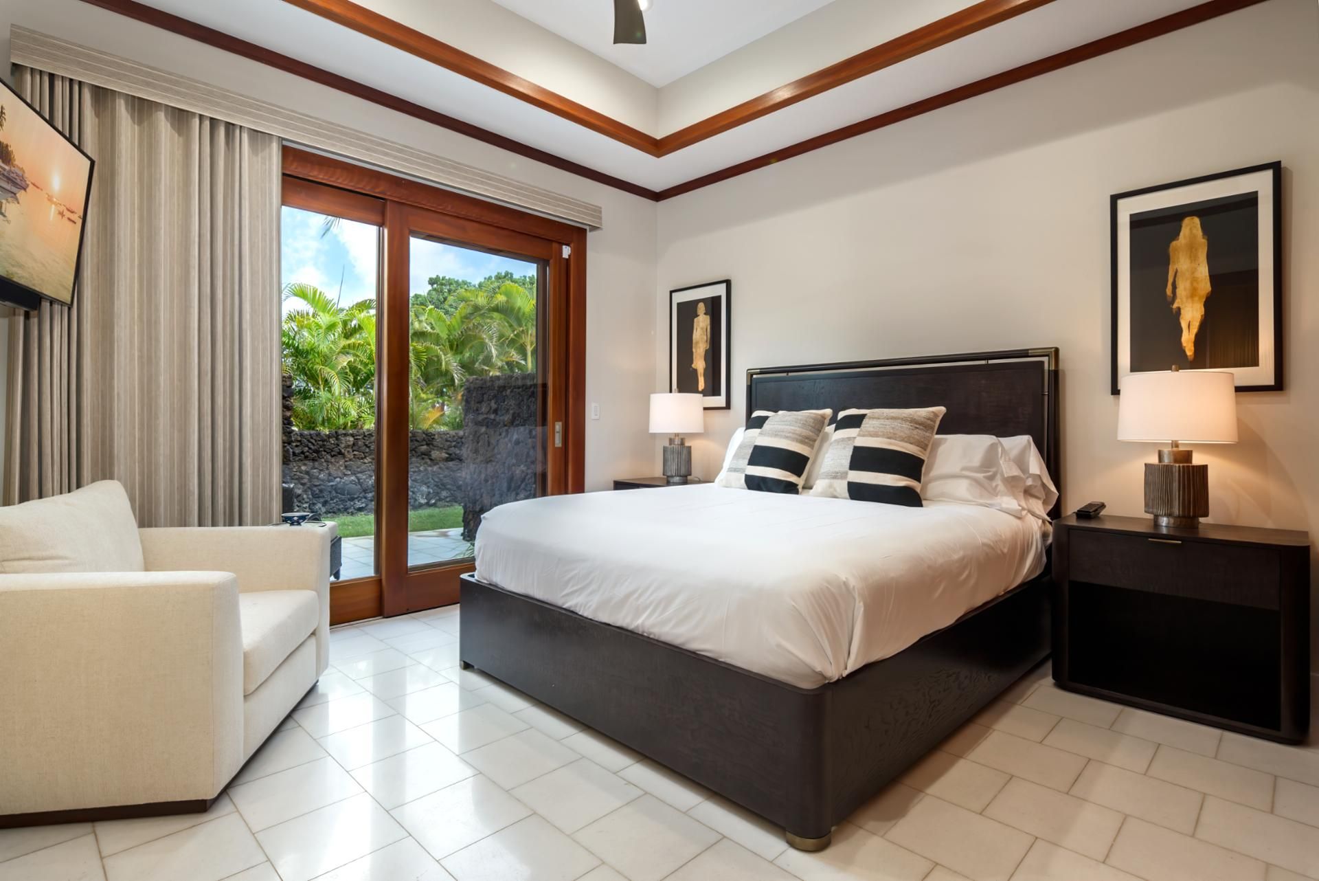 Habitación de hotel con una cama grande, un sofá, una mesita de noche y vistas a zonas verdes.