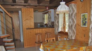 A wooden interior with a dining table, chairs, a kitchen area, and a staircase. - Chrinnenhorn 4 Bett Wohnung by Interhome (Grindelwald)