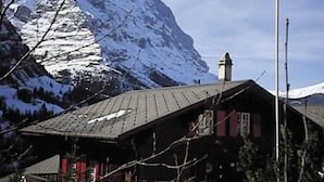 A mountain cabin with a sloped roof, a chimney, and a view of snow-capped mountains. - Chrinnenhorn 4 Bett Wohnung by Interhome (Grindelwald)