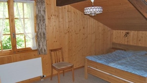 A wooden room with a bed, a chair, a window with curtains, and a ceiling fan. - Chrinnenhorn 4 Bett Wohnung by Interhome (Grindelwald)