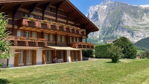 Een traditionele chalet met meerdere balkons, een overdekt terras en een berg als achtergrond.