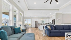 A spacious living area with a grey sofa, a blue sofa, and a white coffee table. - Isle Have Another by Brunswick Vacation Rentals: 7BR w/ Elevator, Pool & Views! (Ocean Isle Beach)