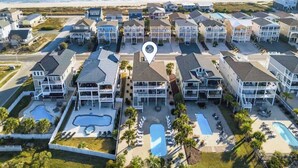 A coastal hotel with multiple buildings, a central pool, and a view of the ocean. - Isle Be Back by Brunswick Vacation Rentals: Oceanfront, Pool, Elevator & Views! (Ocean Isle Beach)