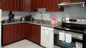 Une cuisine avec des meubles de rangement en bois foncé, une cuisinière en acier inoxydable, un lave-vaisselle et une machine à café.