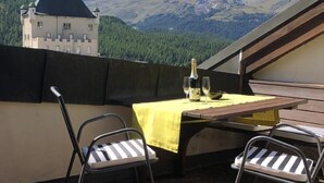 Un patio con una mesa preparada para dos personas, con vistas a un paisaje montañoso.