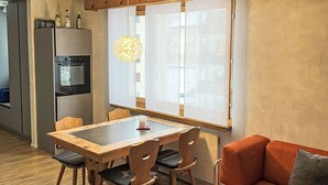 Una cucina compatta con frigorifero, forno e zona pranzo con tavolo e sedie.