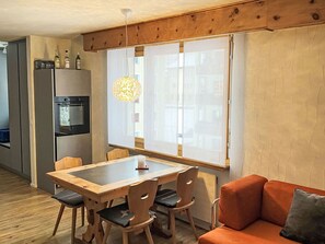 Eine kompakte Küche mit Kühlschrank, Backofen und einem Essbereich mit Tisch und Stühlen.