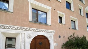 Un edificio con un'ampia porta in legno, diverse finestre e un arco decorativo.