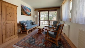 A cozy living room with a sofa, chairs, a coffee table, and a large window with curtains. - Chesa la Furia WHG 24 by Interhome (Pontresina)