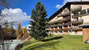 Un hôtel à plusieurs étages doté de balcons, d’une pelouse verdoyante et d’une rivière en arrière-plan.