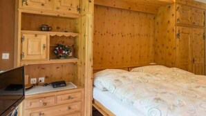 Une pièce en bois avec un lit, un bureau et des placards intégrés.
