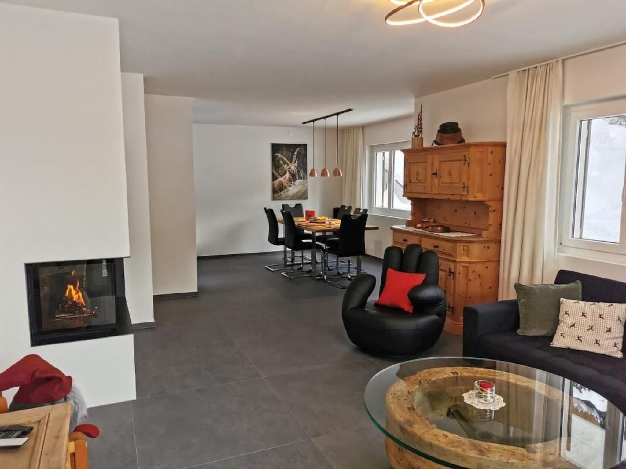 Ein modernes Wohnzimmer mit Kamin, Essbereich und Küche mit Holzausstattung.