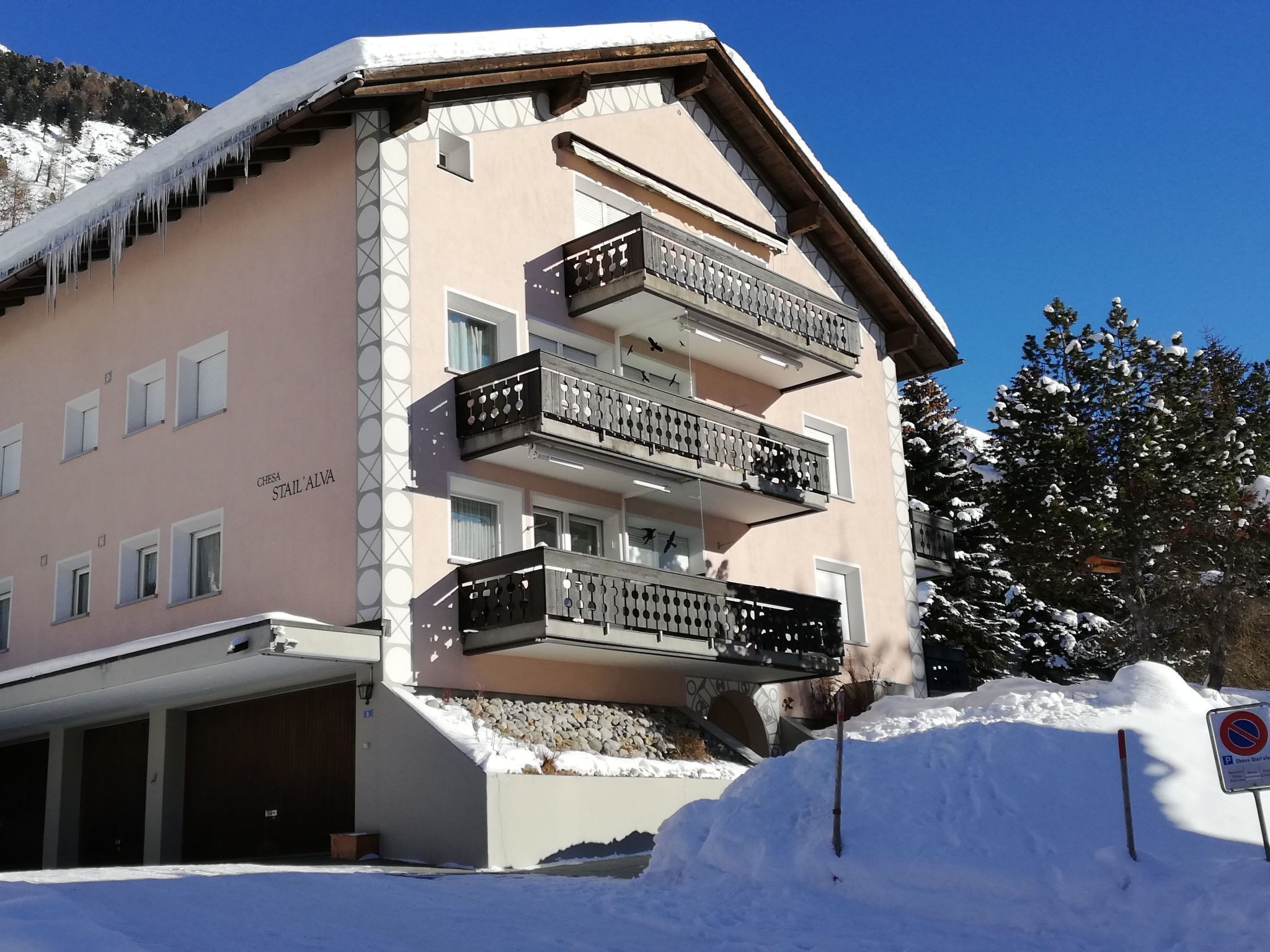 A multi-story building with balconies, a garage, and a snow-covered environment.