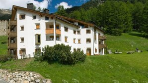 A multi-story building with balconies, surrounded by a grassy landscape and trees. - Chesa Aquileja Trüb by Interhome (Pontresina)