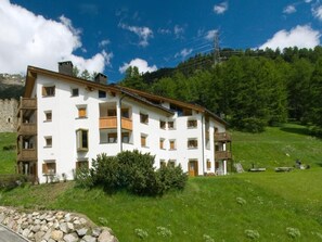 Un edificio de varios pisos con balcones, rodeado de un paisaje cubierto de césped y árboles.