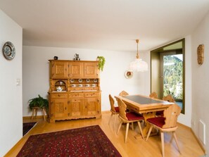 Un coin repas comprenant un buffet en bois, une table, des chaises et un luminaire suspendu.