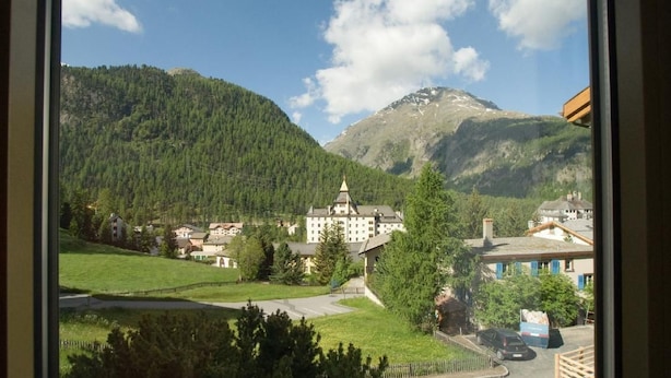 A view of a mountain village with a prominent building in the center, surrounded by lush greenery and a clear sky. - Chesa Aquileja Trüb by Interhome (Pontresina)