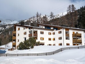 Un hôtel à plusieurs étages, doté de balcons et entouré de montagnes enneigées.