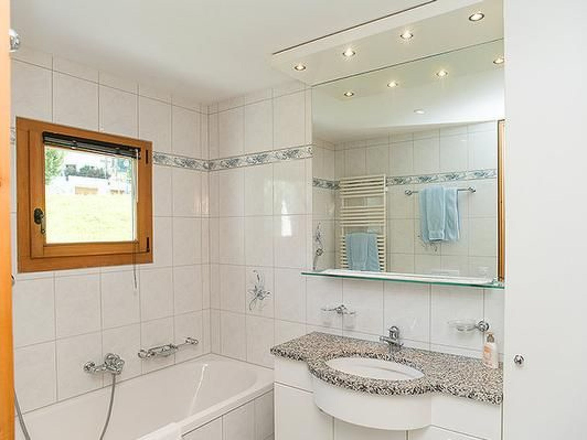 Ein modernes Badezimmer mit Duschkabine aus Glas, einer Badewanne, einem Waschtisch und einem großen Spiegel.