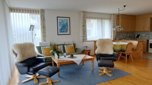 Un salon moderne comprenant un canapé, deux fauteuils, une table basse et un coin repas avec une table et des chaises.