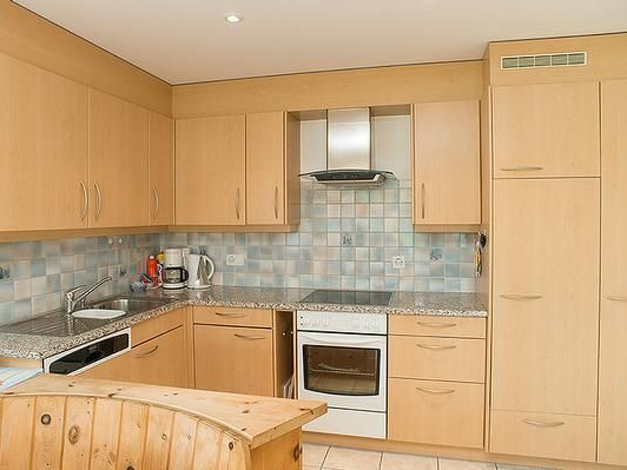 A kitchen with wooden cabinets, a tiled backsplash, a built-in oven, and a coffee maker.