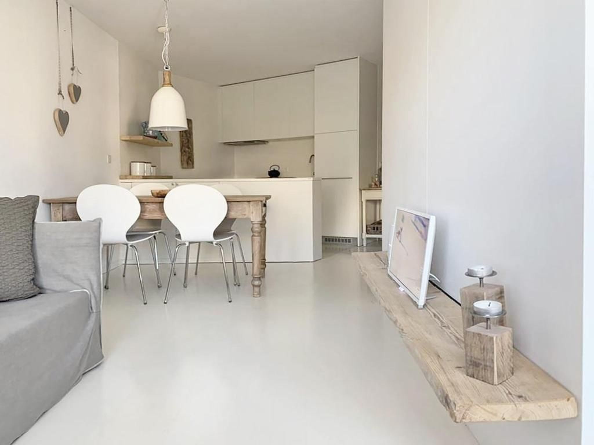 Een moderne keuken met witte kastjes, een houten eettafel en twee witte stoelen.