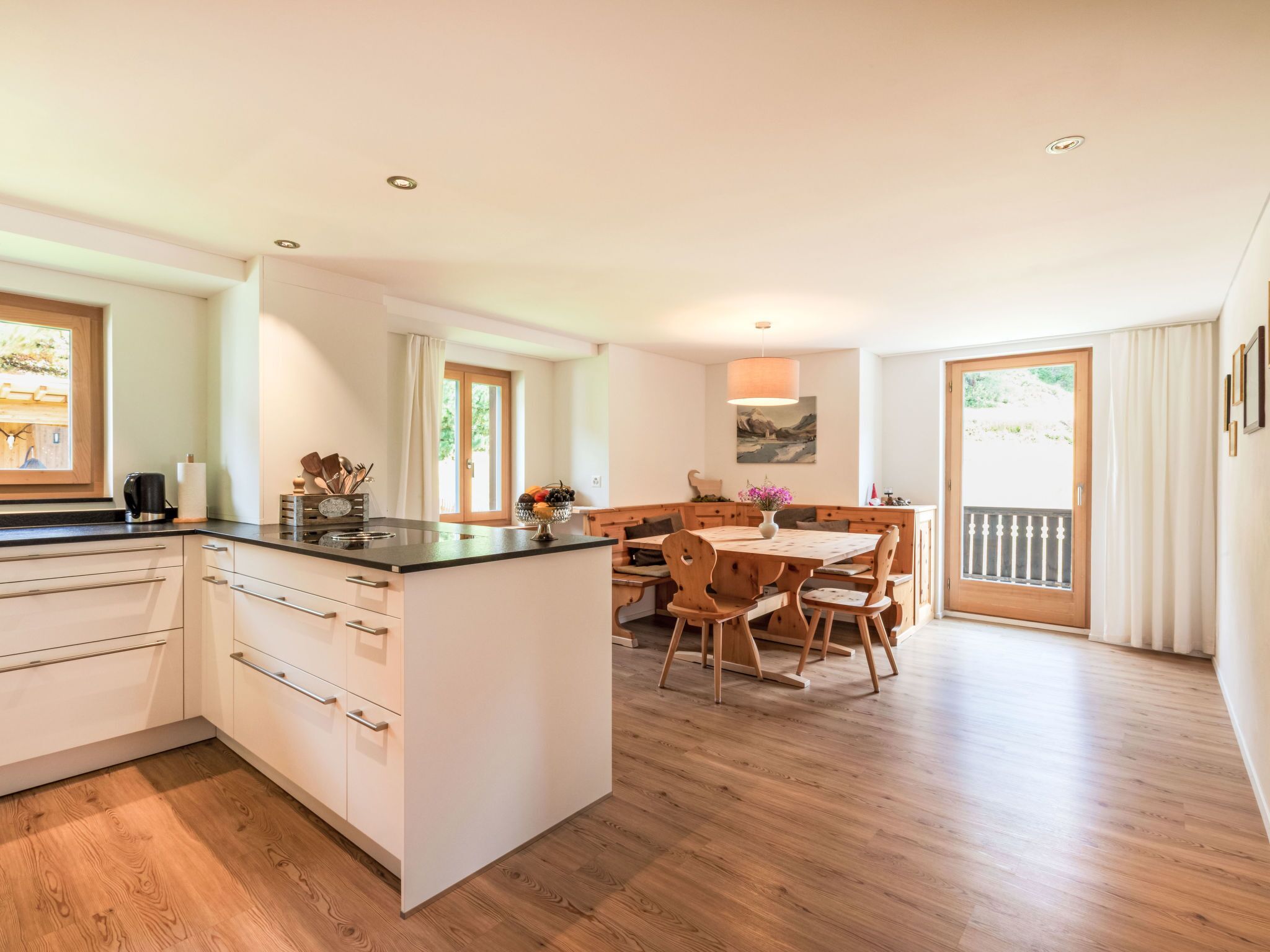 A modern kitchen with a central island, wooden dining table, and chairs.