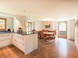 A modern kitchen with a central island, wooden dining table, and chairs. - Chesa Kober - adults only by Interhome (Pontresina)