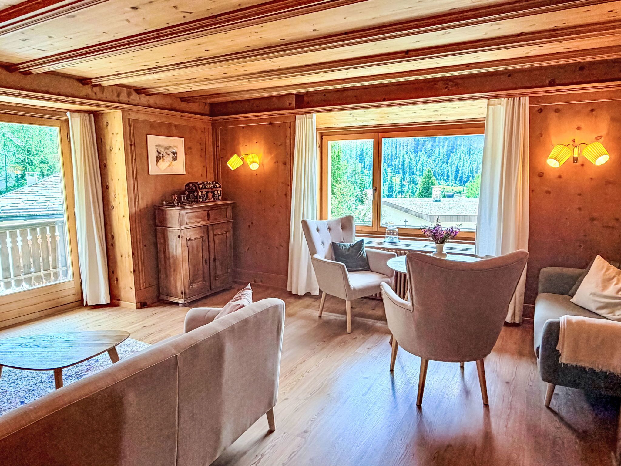A wooden interior with a dining table, chairs, a sofa, and a cabinet.