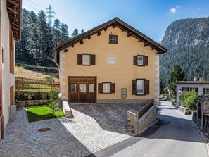 A two-story building with a stone facade, wooden shutters, and a paved courtyard. - Chesa Kober - adults only by Interhome (Pontresina)