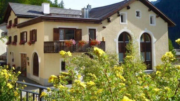 A two-story building with a balcony, arched windows, and a mountain backdrop. - Chesa Thom / ÖV inklusive by Interhome (Pontresina)