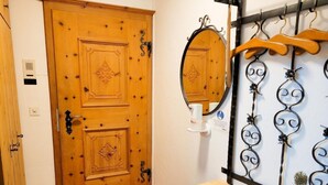 Una porta de fusta amb treballs de talleria detallats, un mirall i una prestatgeria metàl·lica amb penjadors.